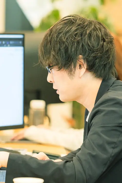 デスクでモニターに向かって作業する男性社員の横顔