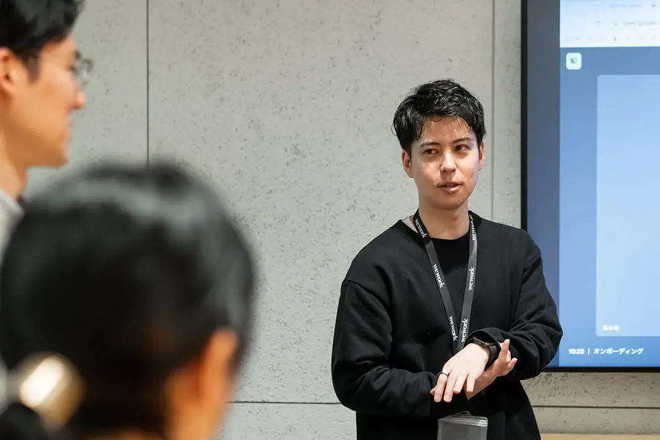 プレゼン中に話す男性と聴講者たちの様子を写したオフィスでの一幕