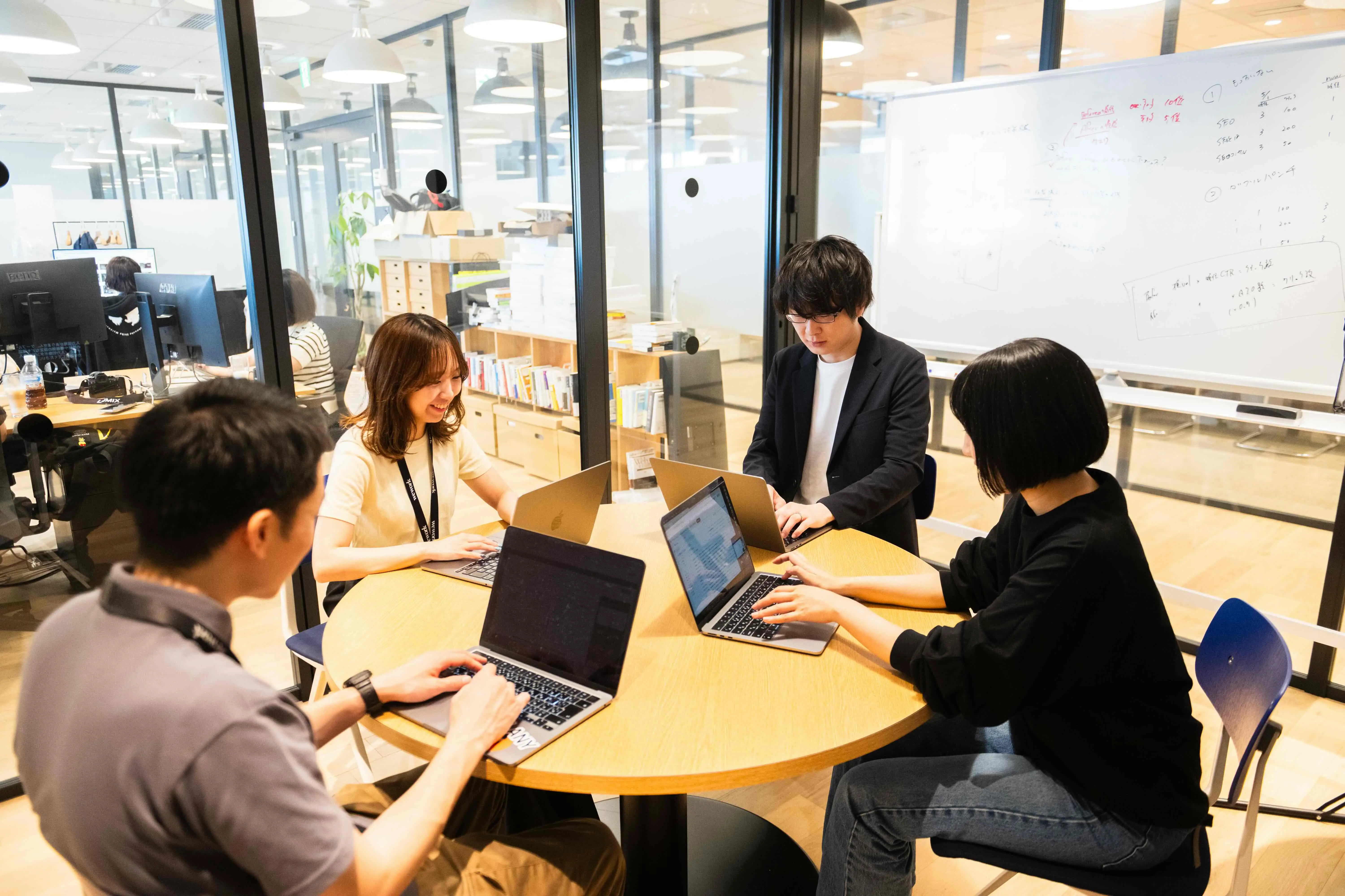 オフィススペースで向かい合って作業をする社員たちのチームワークの様子