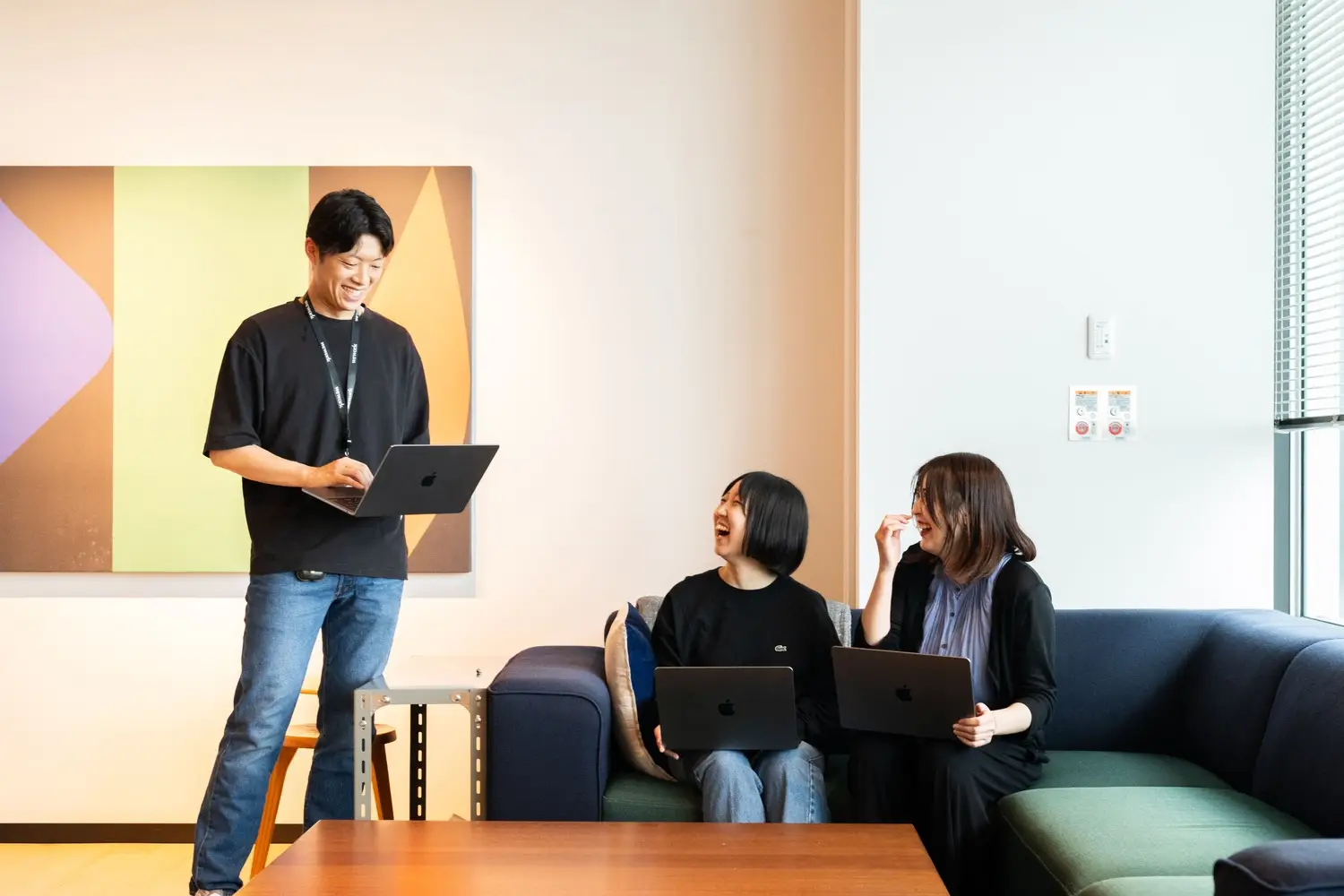 立っている男性社員と座って笑っている女性社員2人