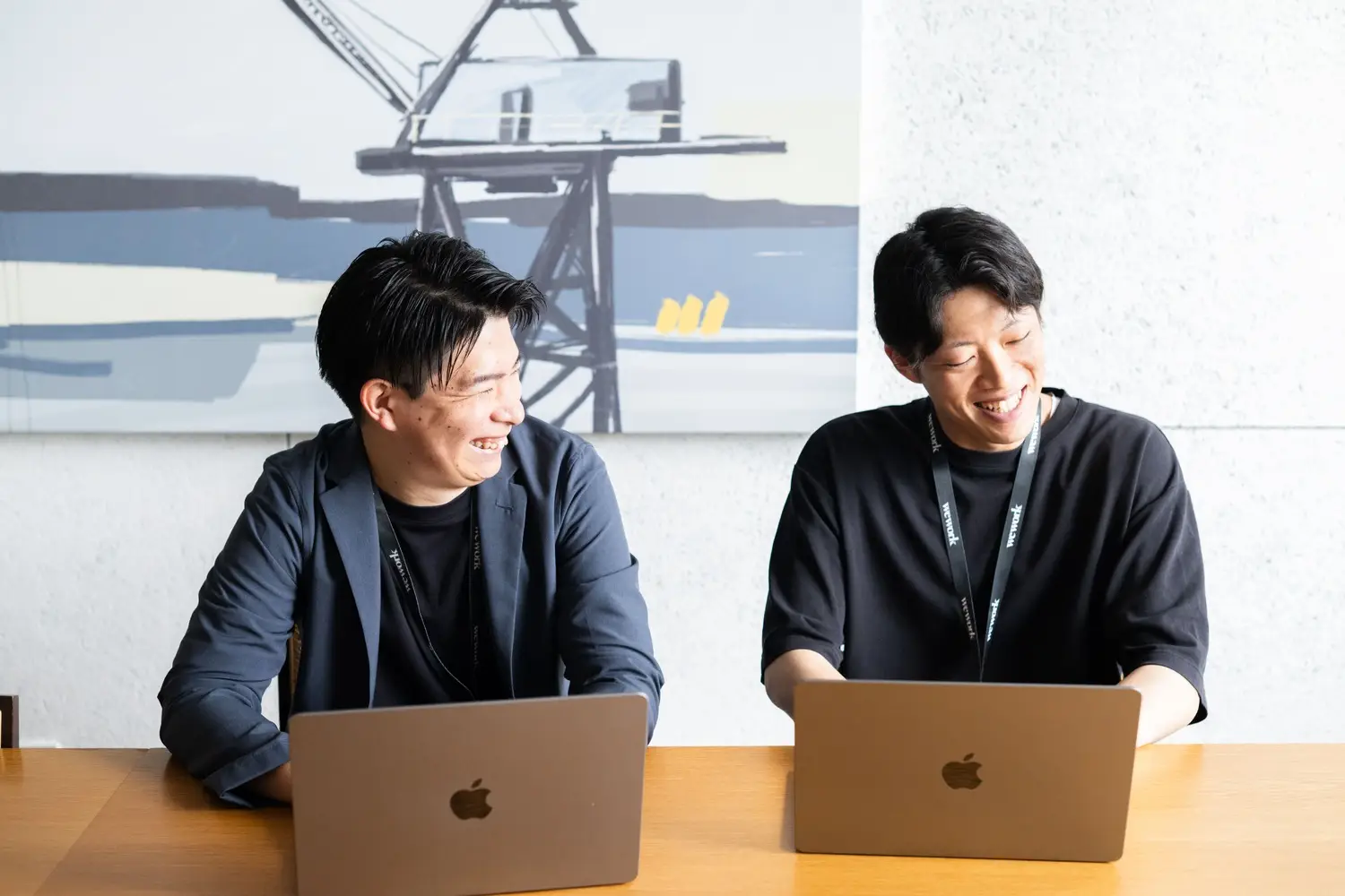 肩を並べて笑顔で仕事をする若手社員2人