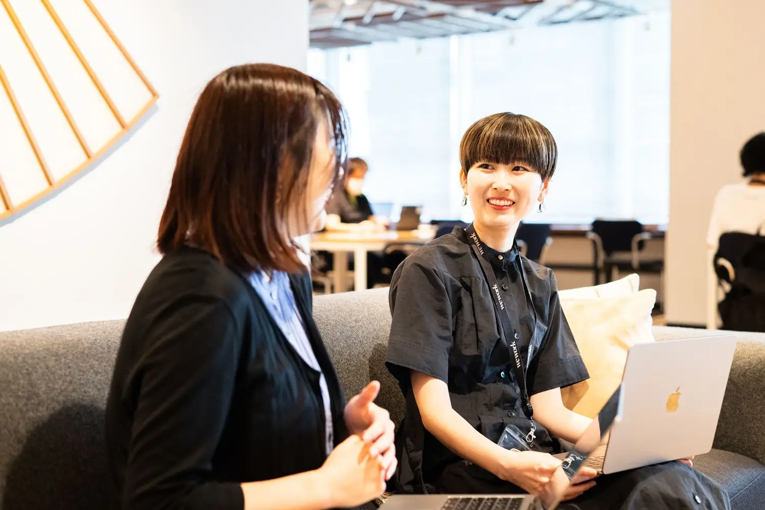 ソファ席で横並びに座って話す女性社員
